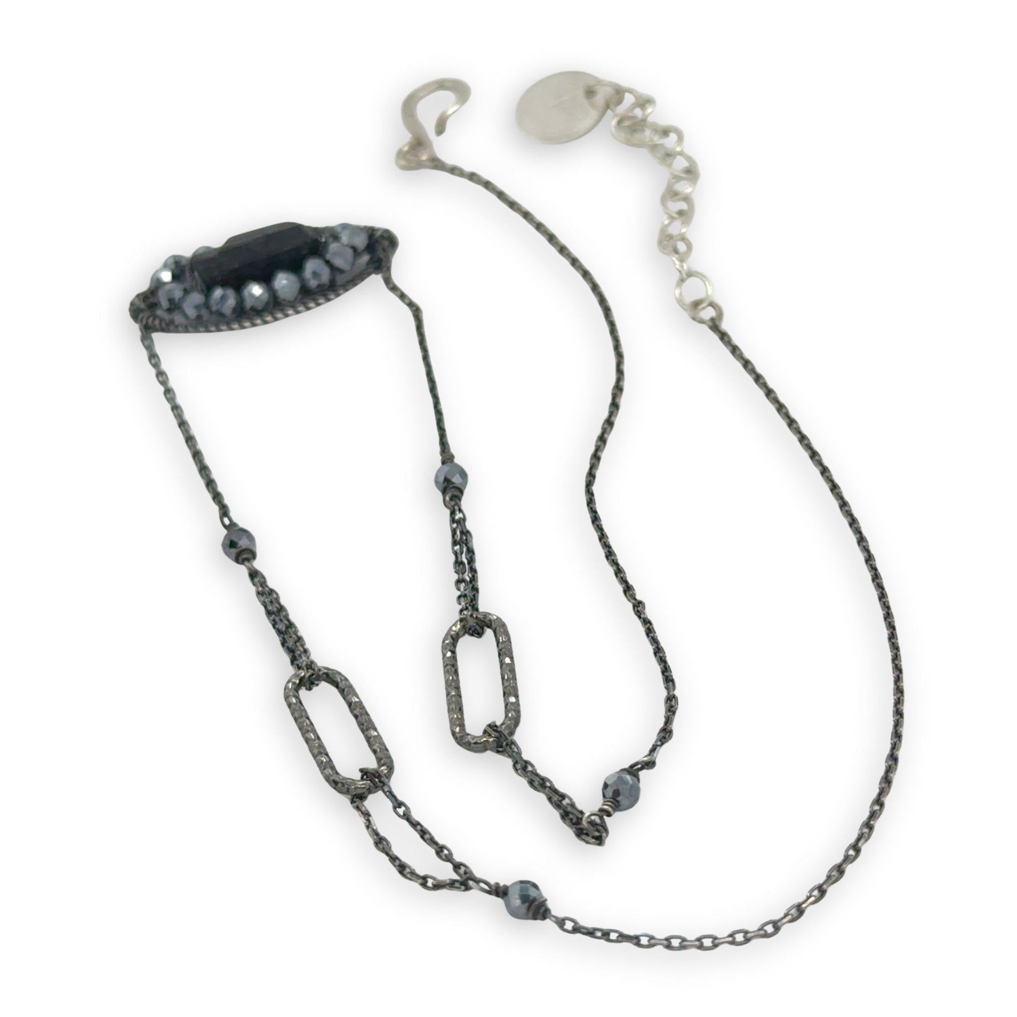 Black beaded necklace with chain on a white background