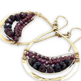 Gold hoop earrings with garnet gemstones on a white background