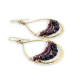 Gold earrings with garnet gemstones on a white background