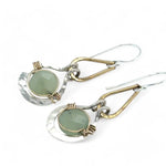 Pair of earrings with green jade gemstones and gold and silver accents on a white background