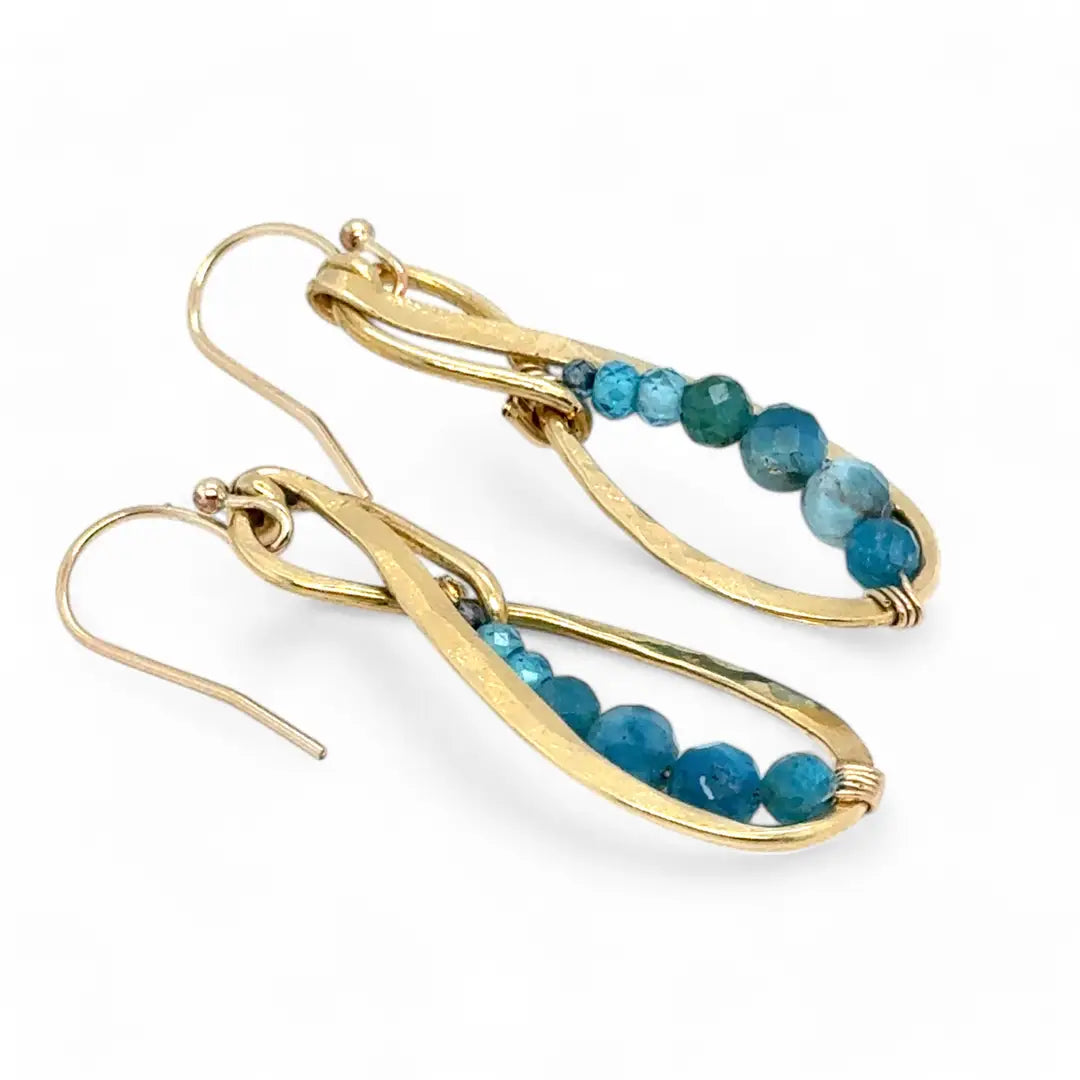 Gold earrings with blue apatite beads on a white background