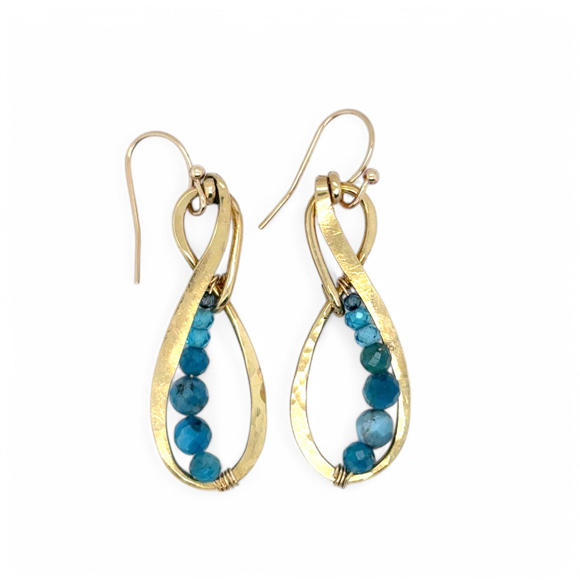 A pair of gold-colored infinity earrings with blue apatite faceted gemstones attached to them.