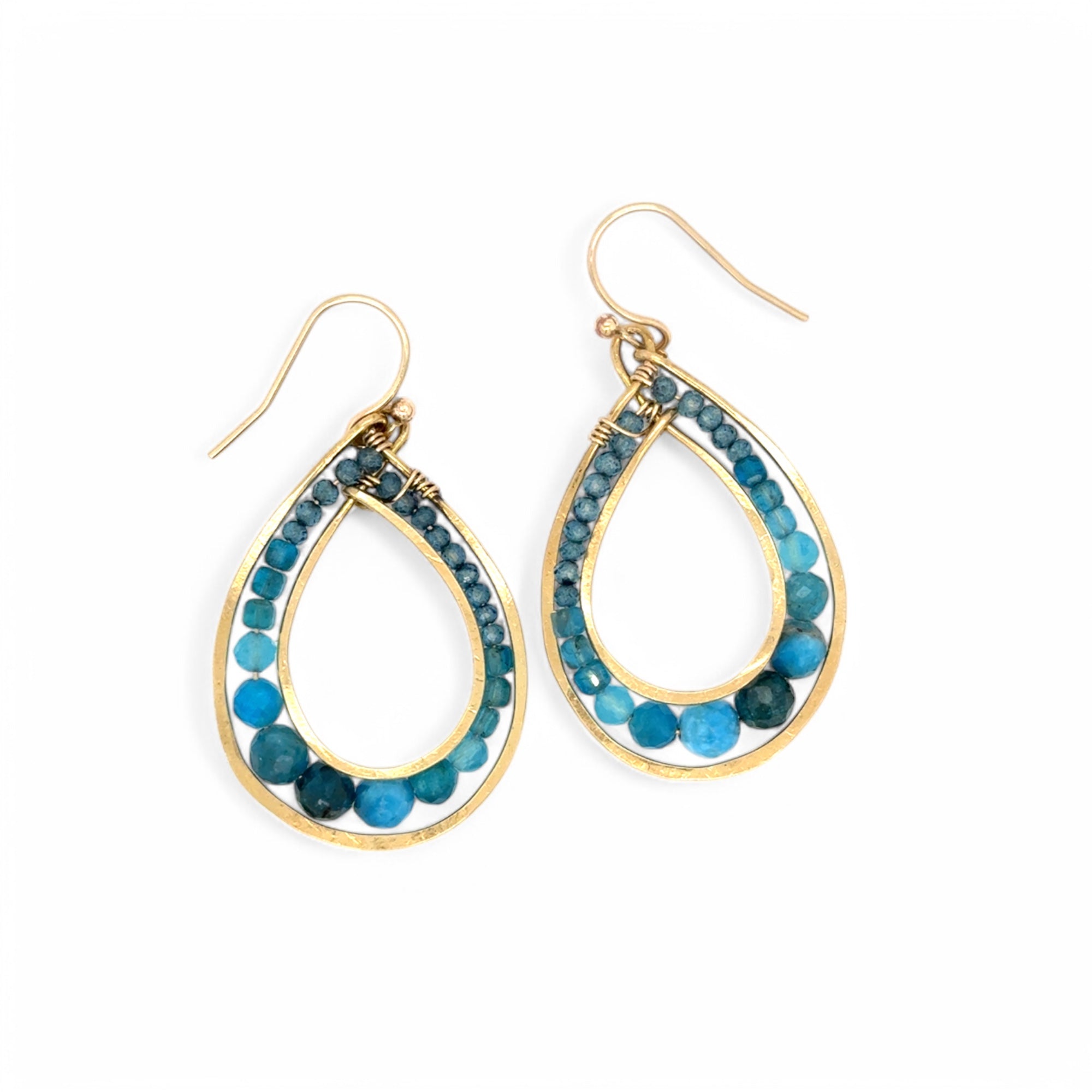 A pair of gold-filled bronze channel hoop earrings with blue apatite gemstones, featuring gold-filled French hooks.