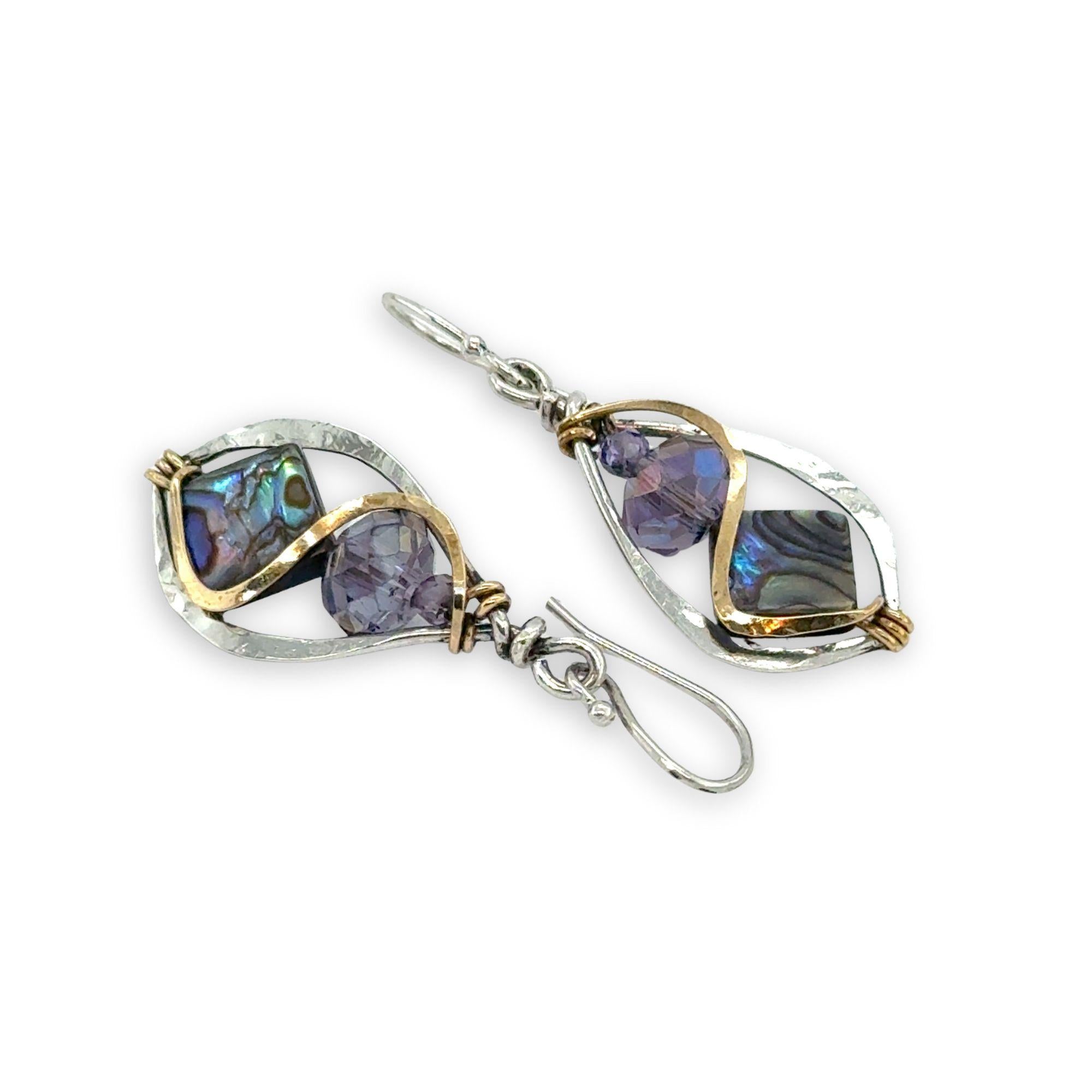Pair of earrings with purplecrystals and abalone gemstones and gold accents on a white background