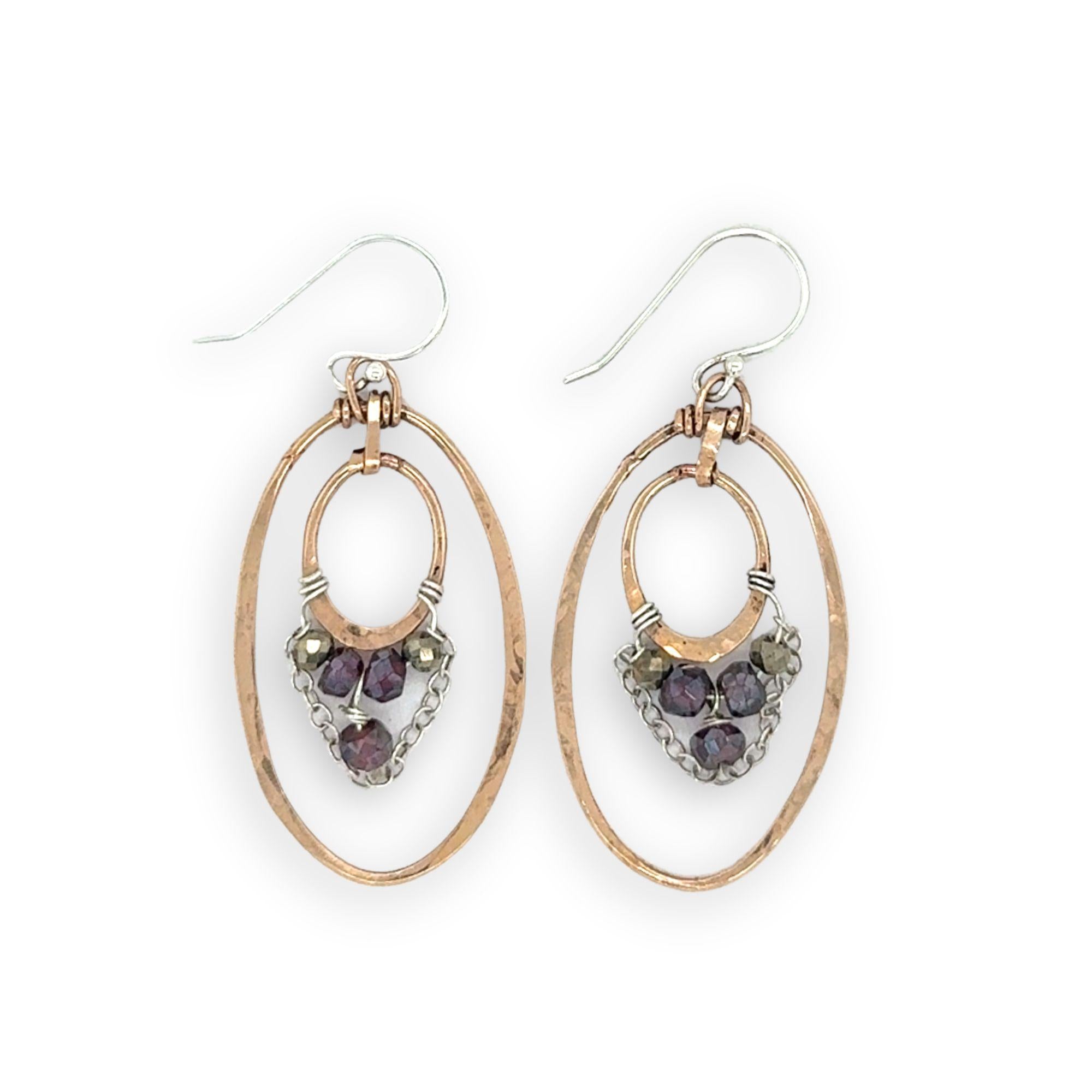 Pair of gold and silver earrings with purple gemstones on a white background