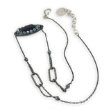 Black beaded necklace with chain on a white background