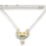 A delicate necklace with a crescent-shaped pendant featuring gold-toned metal, pale pearls, and green gemstone accents, suspended from a fine chain on a white background.