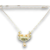 A delicate necklace with a crescent-shaped pendant featuring gold-toned metal, pale pearls, and green gemstone accents, suspended from a fine chain on a white background.