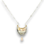 A delicate silver chain necklace featuring a crescent-shaped pendant with freshwater pearls, clear crystals, and a dangling pearl bead, set against a plain white background.