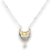 A delicate silver chain necklace featuring a crescent-shaped pendant with freshwater pearls, clear crystals, and a dangling pearl bead, set against a plain white background.