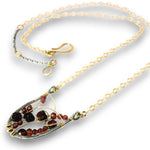 A delicate gold chain necklace with a unique teardrop-shaped pendant. The pendant features a textured silver-tone base, wrapped with gold wire, and set with dark brown and reddish-brown gemstone beads, photographed on a clean white background.