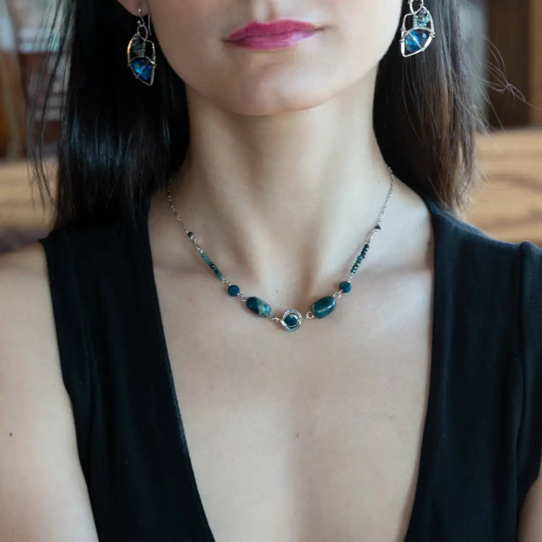 Close-up of a woman wearing a necklace with blue apatite stones and earrings.