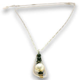 A delicate necklace featuring a large white pearl and dark green beads set in gold-toned metal, suspended from a thin cream-colored chain with an adjustable sliding clasp.