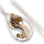 A teardrop-shaped pendant necklace featuring a silver-toned textured frame, a faceted brown gemstone, small dark brown beads, and a teardrop-shaped smoky brown bead, suspended on a silver link chain against a white background.