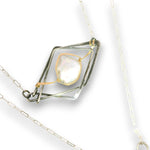 A silver and gold geometric pendant necklace featuring a central iridescent white stone, displayed on a clean white background.