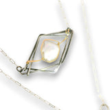 A silver and gold geometric pendant necklace featuring a central iridescent white stone, displayed on a clean white background.