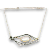 A silver-toned geometric pendant necklace featuring a central baroque pearl wrapped with delicate gold wire, suspended on a fine silver chain against a white background.