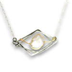 A silver-toned geometric pendant necklace featuring a central teardrop-shaped iridescent white pearl held by gold-toned wire within a layered diamond frame, suspended from a silver link chain.