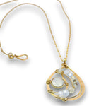 A gold teardrop pendant necklace featuring a large oval clear gemstone and smaller faceted white and iridescent beads, shown on a white background.