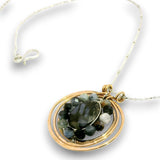 A gold and silver wire-wrapped pendant necklace featuring a faceted dark green labradorite stone and small accent beads, shown on a clean white background.