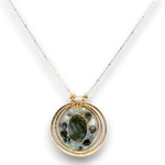 A gold and silver chain necklace featuring a circular pendant with a central dark green stone surrounded by small dark stones, set against a clean white background.