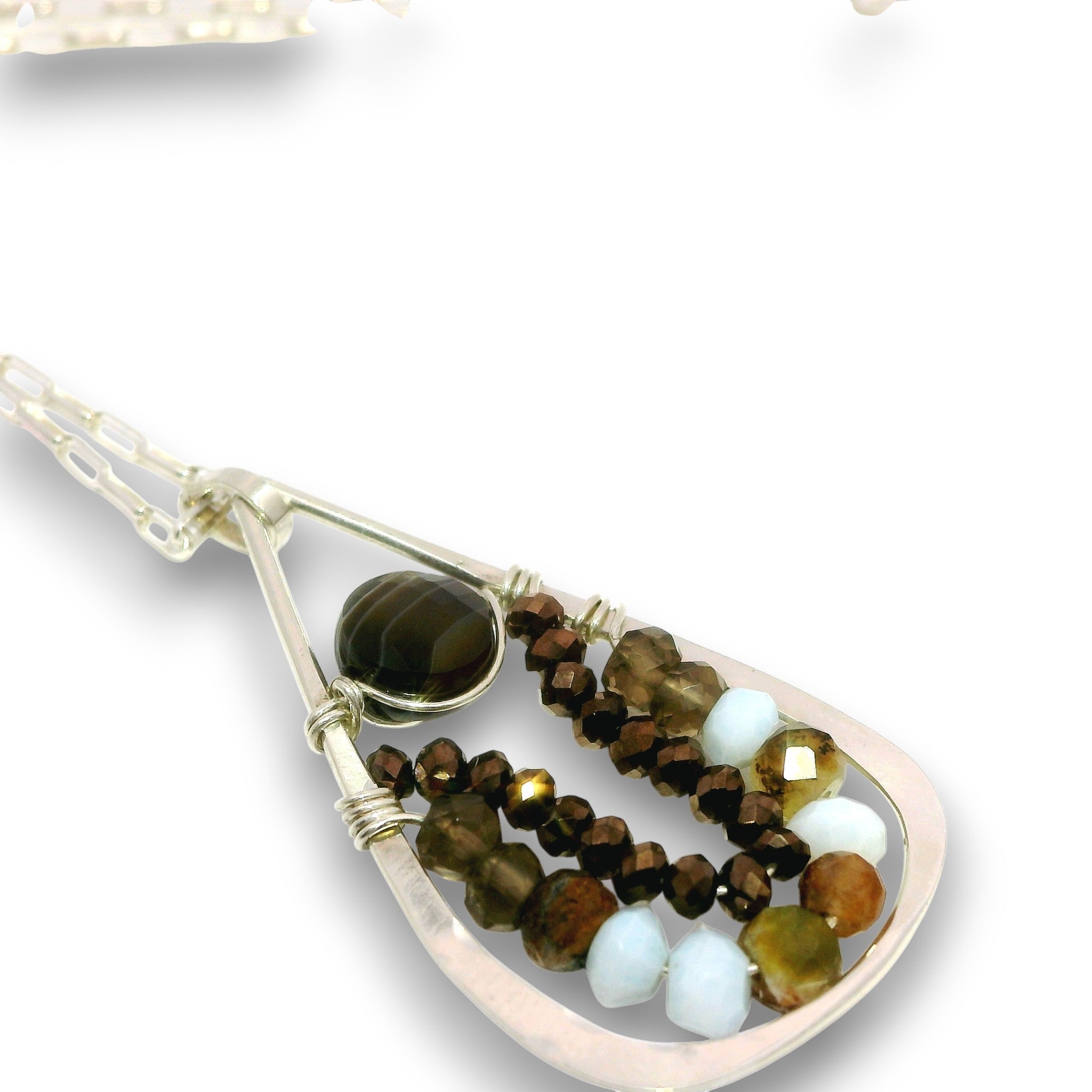 A close-up of a teardrop-shaped pendant necklace featuring a silver-toned frame, a dark brown tiger's eye bead, and multiple strands of faceted beads in brown, gold, and pale blue, set against a plain white background.