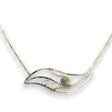 A delicate necklace featuring a wave-like pendant made of textured silver and gold wire, with a small round gray stone in the center, set against a plain white background.