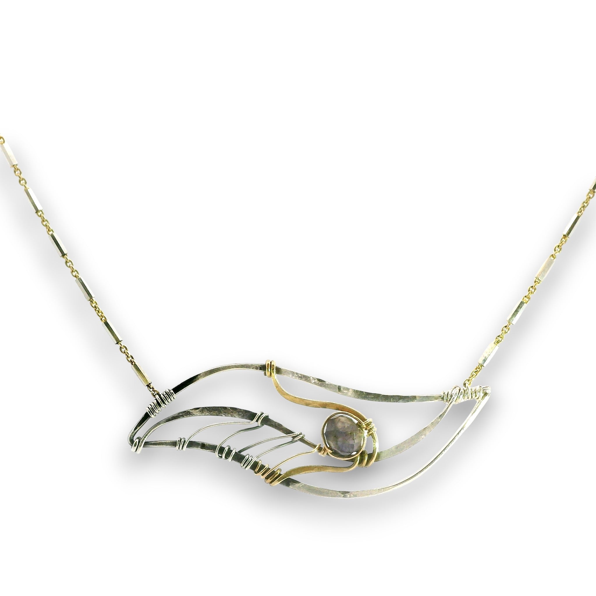 A delicate necklace featuring a wave-like pendant made of textured silver and gold wire, with a small round gray stone in the center, set against a plain white background.
