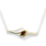 A gold-toned necklace featuring a geometric open-frame pendant with a central brown tiger's eye stone, shown against a plain white background.