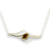 A gold-toned necklace featuring a geometric open-frame pendant with a central brown tiger's eye stone, shown against a plain white background.
