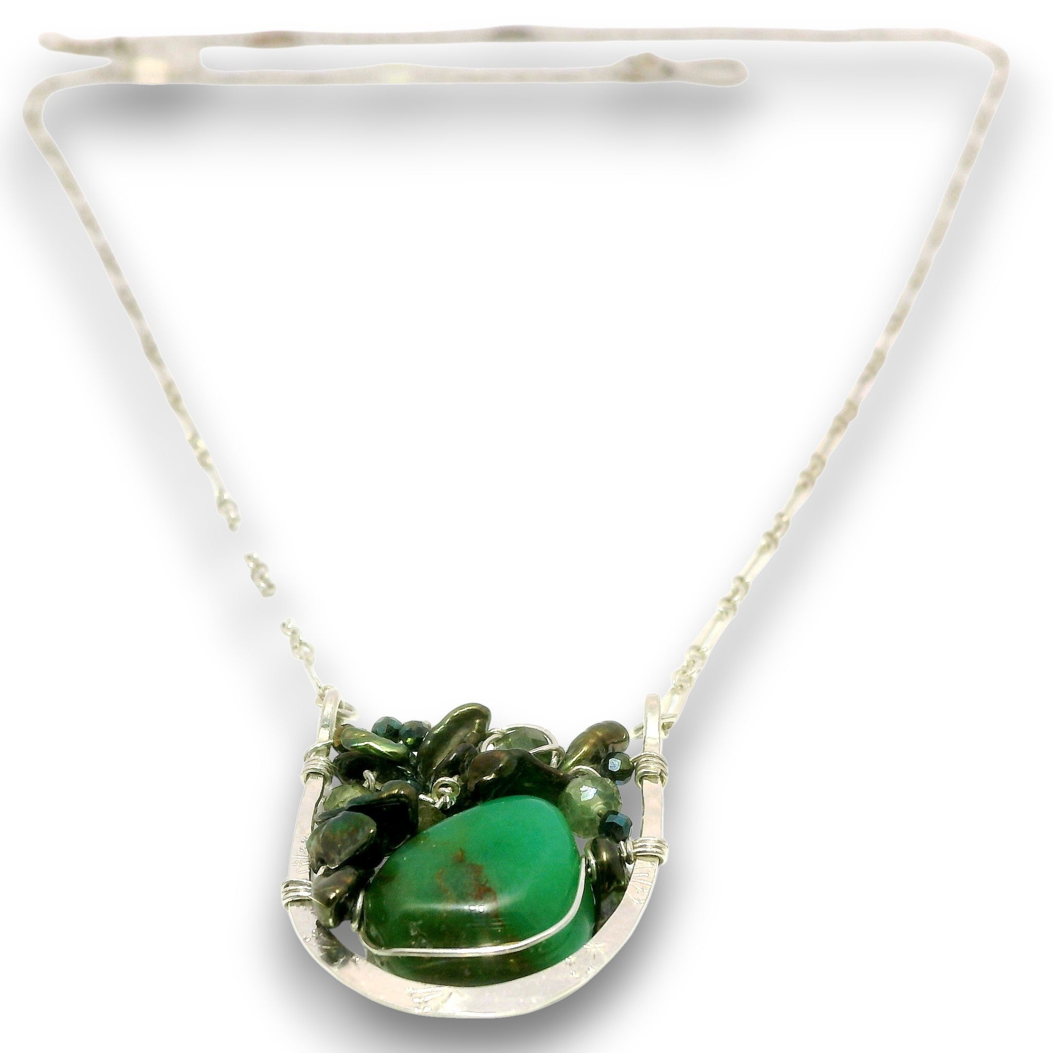 A sterling silver necklace featuring a unique pendant with a large polished green stone surrounded by smaller green stones and leaves, suspended on a delicate silver chain.