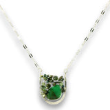 A silver chain necklace with a pendant featuring a vibrant green stone surrounded by small green crystals and gold-toned metal details, set against a plain white background.