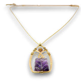A gold chain necklace with a teardrop-shaped pendant featuring a purple amethyst stone and a small brown gemstone, set against a plain white background.