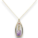 A gold pendant necklace featuring a teardrop-shaped bezel set with a purple amethyst crystal and a small round pink stone, suspended from a delicate gold chain against a white background.
