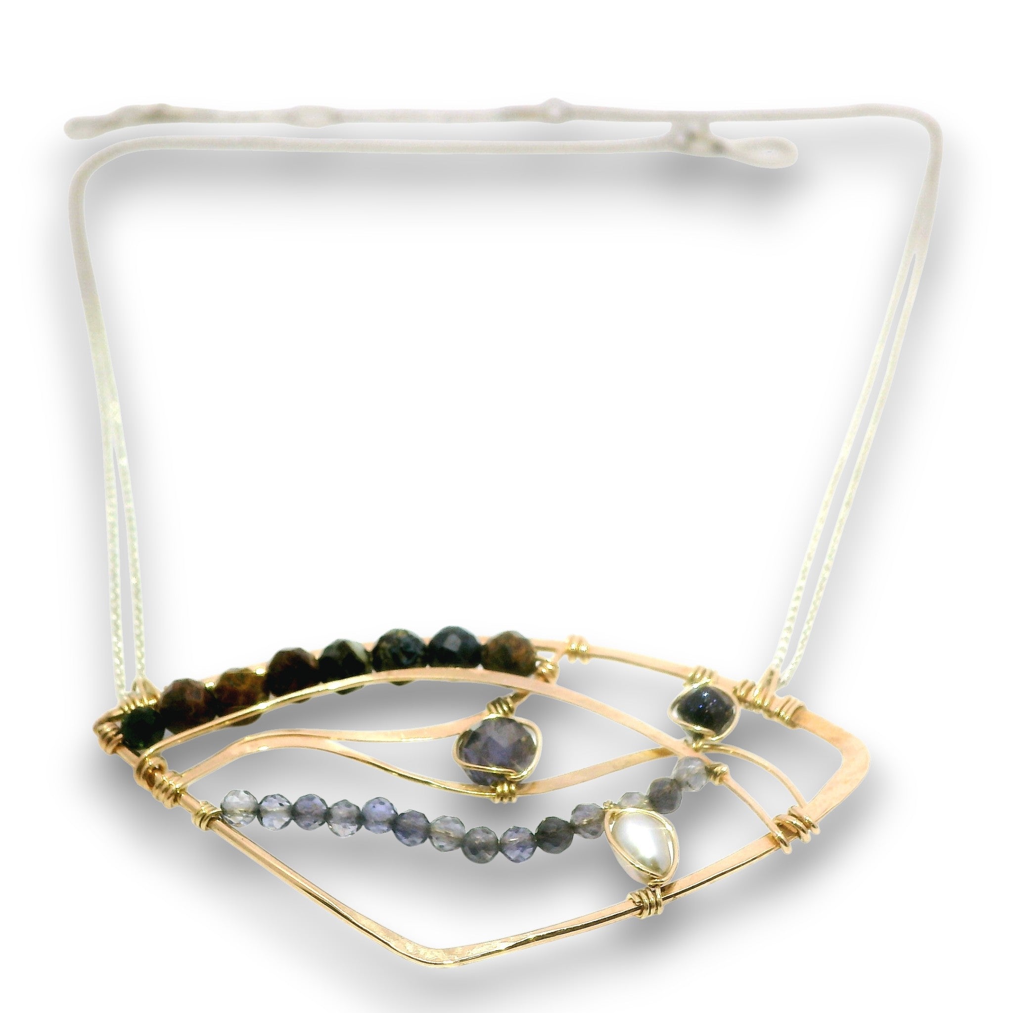 A gold-toned geometric necklace with a white adjustable cord, featuring dark green and brown beads, a row of gray beads, and a central clear teardrop gemstone.