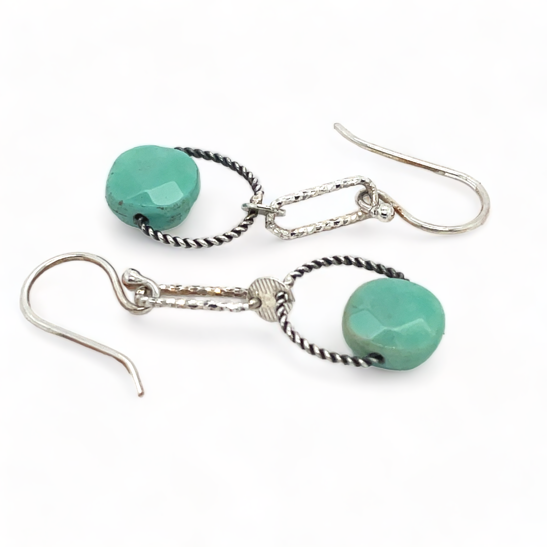 A pair of earrings featuring green chrysoprase stones on sterling silver hooks and twisted rings.