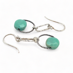 A pair of earrings featuring green chrysoprase stones on sterling silver hooks and twisted rings.