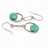 A pair of earrings featuring green chrysoprase stones on sterling silver hooks and twisted rings.