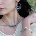 A sterling silver and brass hammered cuff bracelet featuring a single blue amazonite gemstone, with a twist design and an interlocked structure.