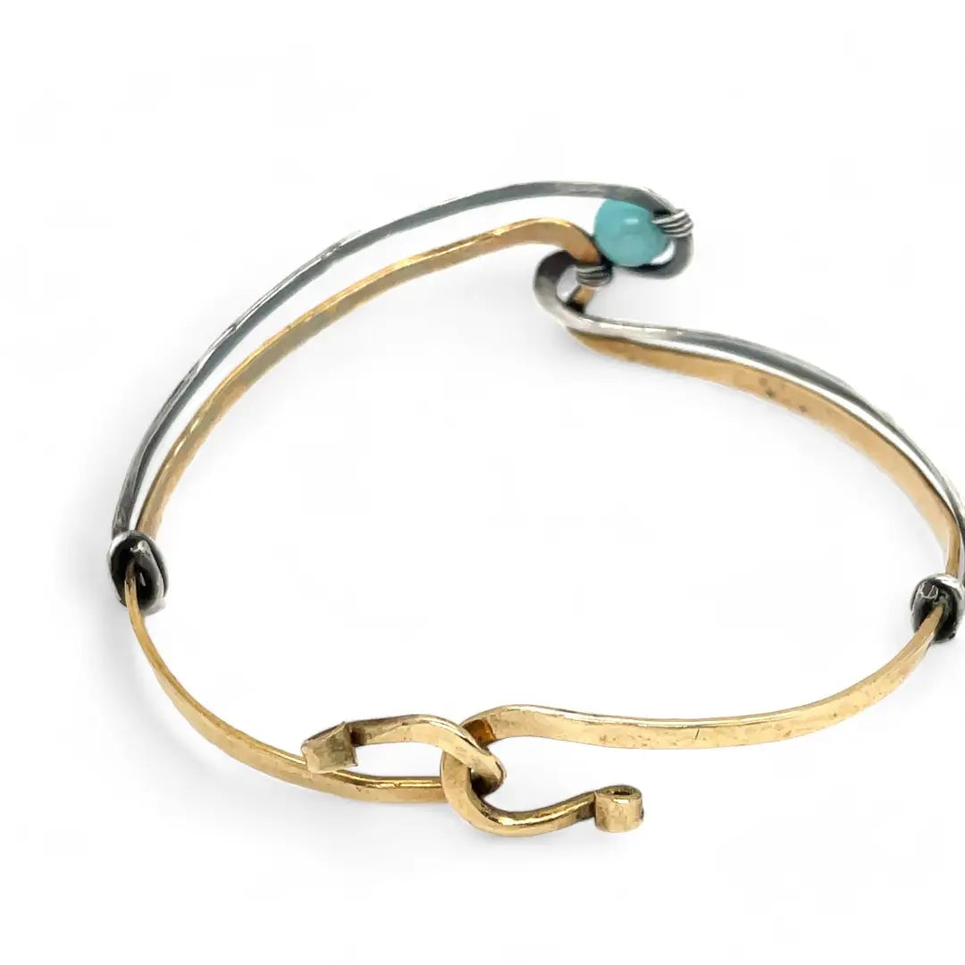 A sterling silver and brass hammered cuff bracelet featuring a single blue amazonite gemstone, with a twist design and an interlocked structure.