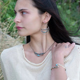 A sterling silver and brass hammered cuff bracelet featuring a single blue amazonite gemstone, with a twist design and an interlocked structure.