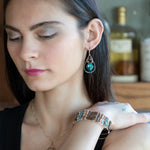 A pair of sterling silver drop earrings with gold filled wire, featuring chrysocolla drop gemstones, chocolate freshwater pearls, and chocolate striped agate.