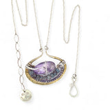 A sterling silver adjustable chain necklace with a hammered handmade brass pendant featuring a glowing amethyst smooth pebble, surrounded by faceted blue zoisite and micro faceted lavender cubic zirconia gemstones.