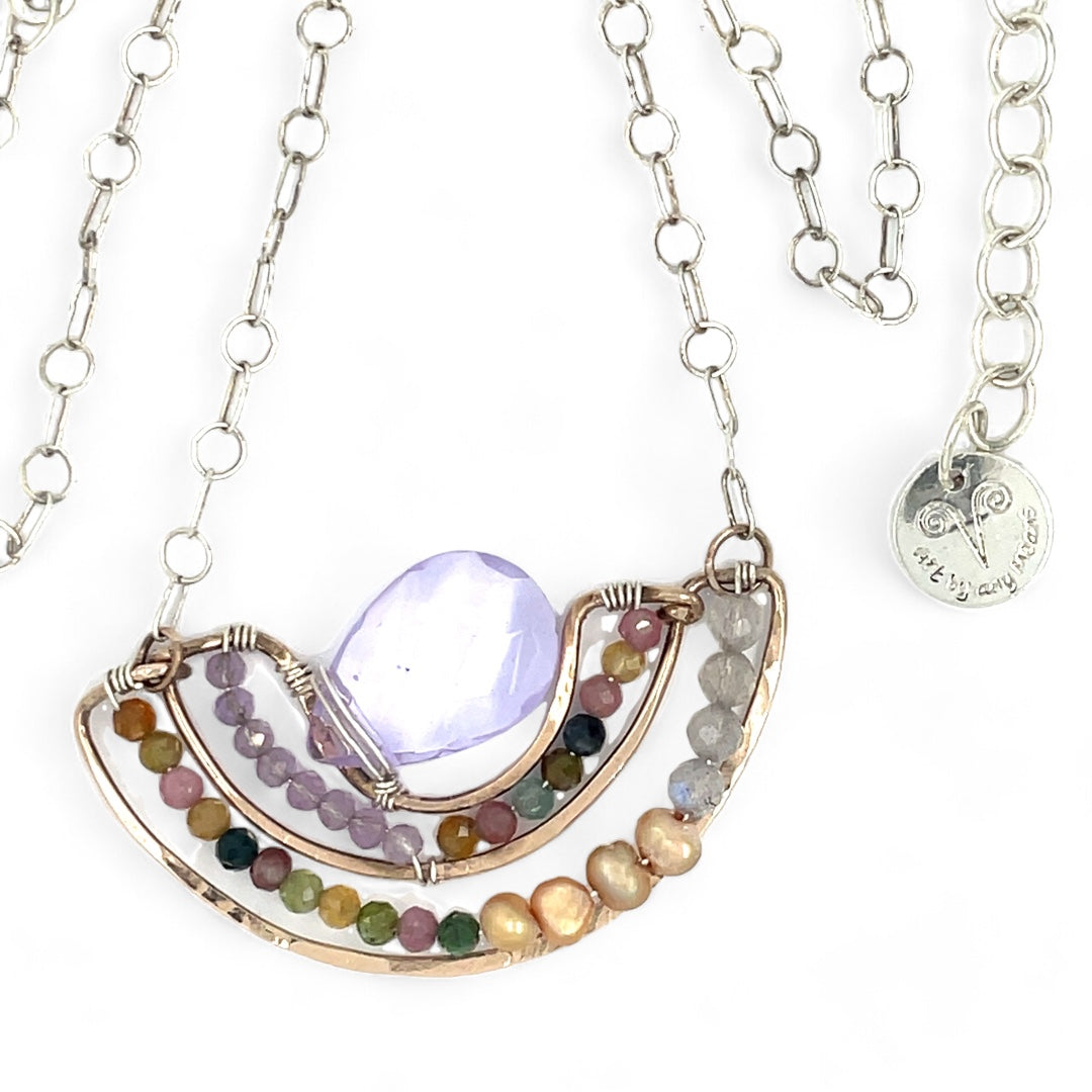 A handmade bronze necklace featuring a layered design with a faceted teardrop-shaped lavender quartz, tourmaline, amethyst, and labradorite gemstones, accompanied by golden fresh water with an adjustable chain and a signature clasp.