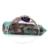 A handcrafted sterling silver bracelet featuring a faceted drop of dark amethyst and other amethyst gemstones in hammered brass, accompanied by micro-faceted cubic zirconia