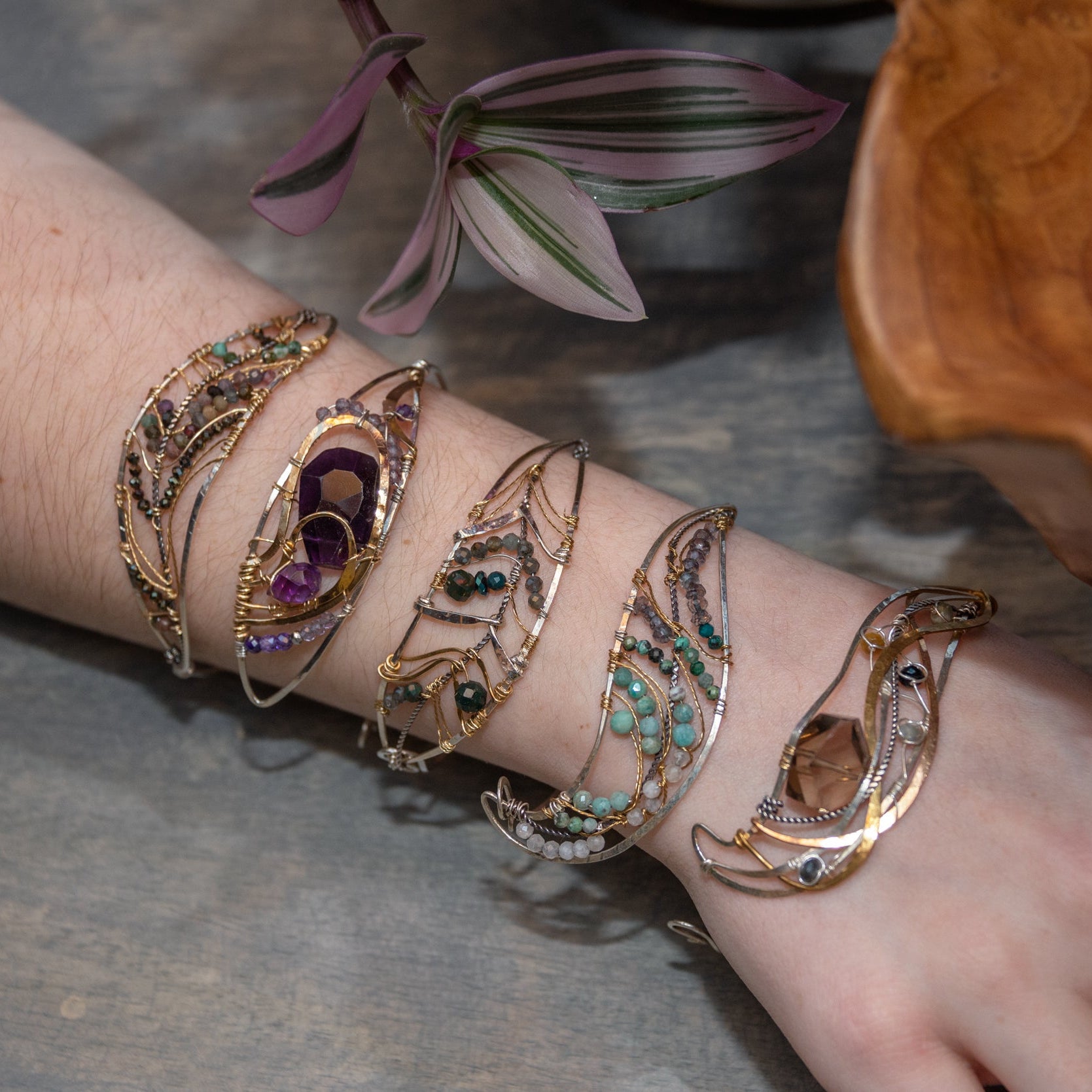 A handcrafted sterling silver bracelet featuring a faceted drop of dark amethyst and other amethyst gemstones in hammered brass, accompanied by micro-faceted cubic zirconia