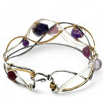 A collection of faceted amethyst nuggets, pink sapphire, and ruby gemstones are wrapped in gold filled wire onto a bracelet formed of leaf stamped oxidized sterling, bright sterling, and bronze hammered waves