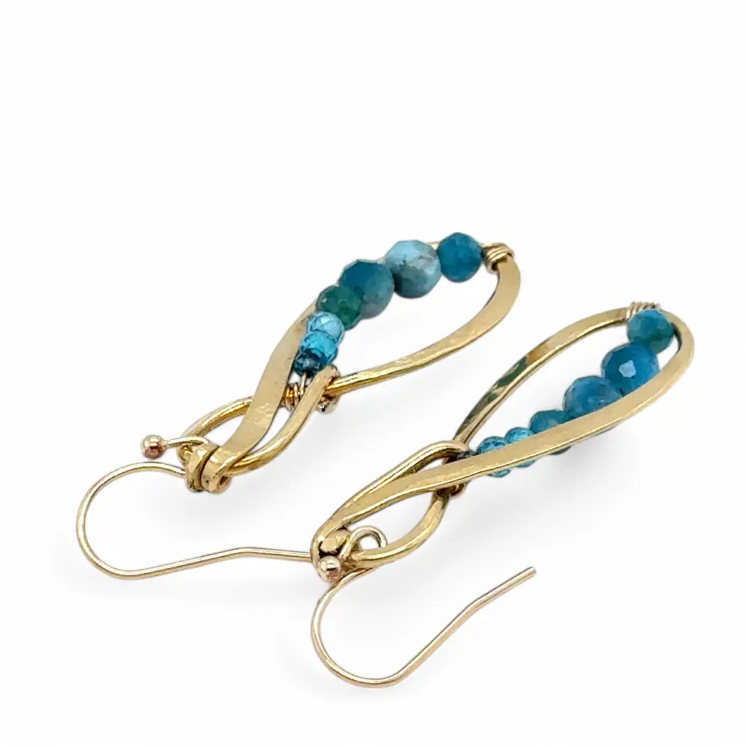 A pair of hammered brass infinity earrings with blue apatite and opal faceted gemstones on gold filled wire