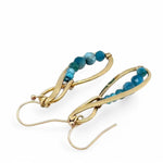 A pair of hammered brass infinity earrings with blue apatite and opal faceted gemstones on gold filled wire