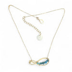 A brass infinity-shaped pendant necklace with blue faceted apatite and opal gemstones on the inside, attached to a gold-filled chain with an adjustable clasp